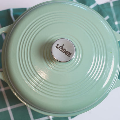 Someone lifting lid on dutch oven revealing fresh tortilla soup garnished with limes.