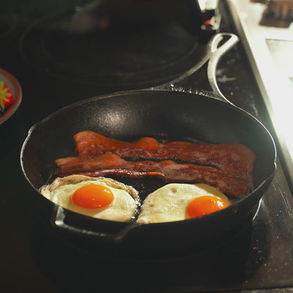 Bacon and eggs cooking in skillet.