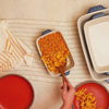 Fresh Macaroni and cheese being served from indigo casserole dish.