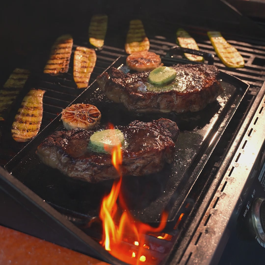 Steaks cooking on griddle with butter and garlic.