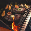Steaks cooking on griddle with butter and garlic.