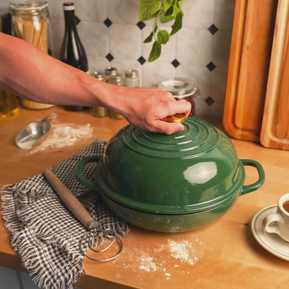 Someone lifting lid off of bread oven, revealing steam and a beautifully baked bread.