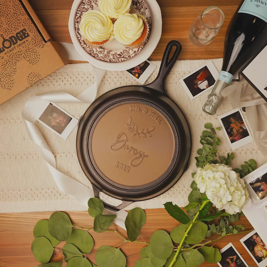 Close-up view of personalized skillet with a wedding backdrop and cupcakes.