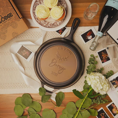 Close-up view of personalized skillet with a wedding backdrop and cupcakes.