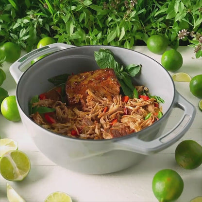 Someone lifting lid on dutch oven revealing a freshly made dish.
