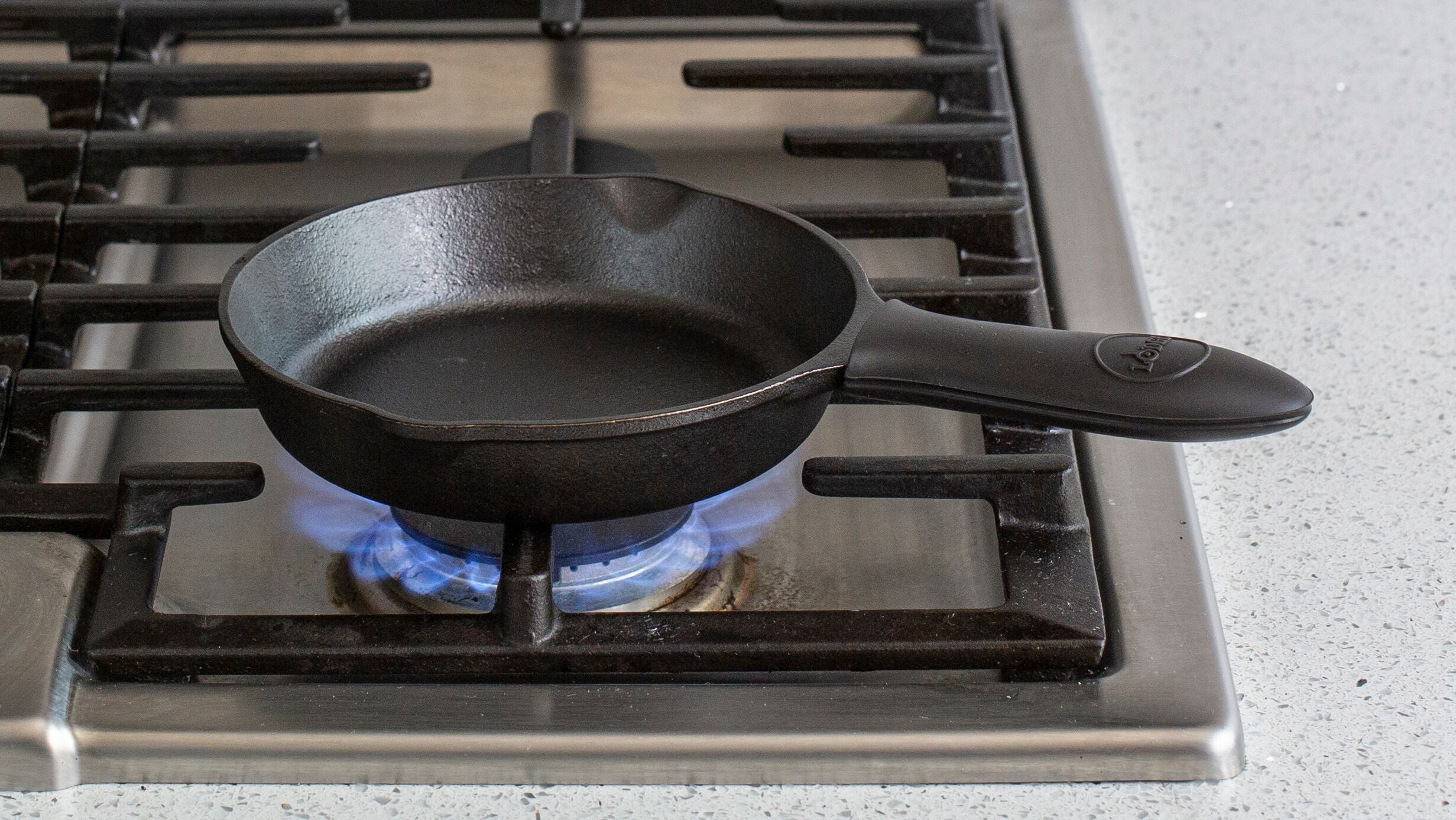Silicone handle holder on skillet cooking on stove.